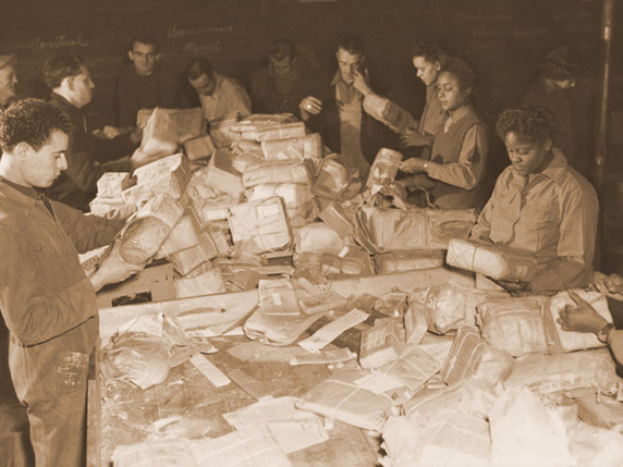 French civilians and soldiers from the 6888th Central Postal Directory Battalion sort mail in France during the spring of 1945. Viewing their jobs as crucial to morale at the front, they processed some 65,000 pieces of mail a shift and worked three shifts a day. At the same time, the soldiers faced constant prejudice and broke gender and racial barriers. Army photo. -
