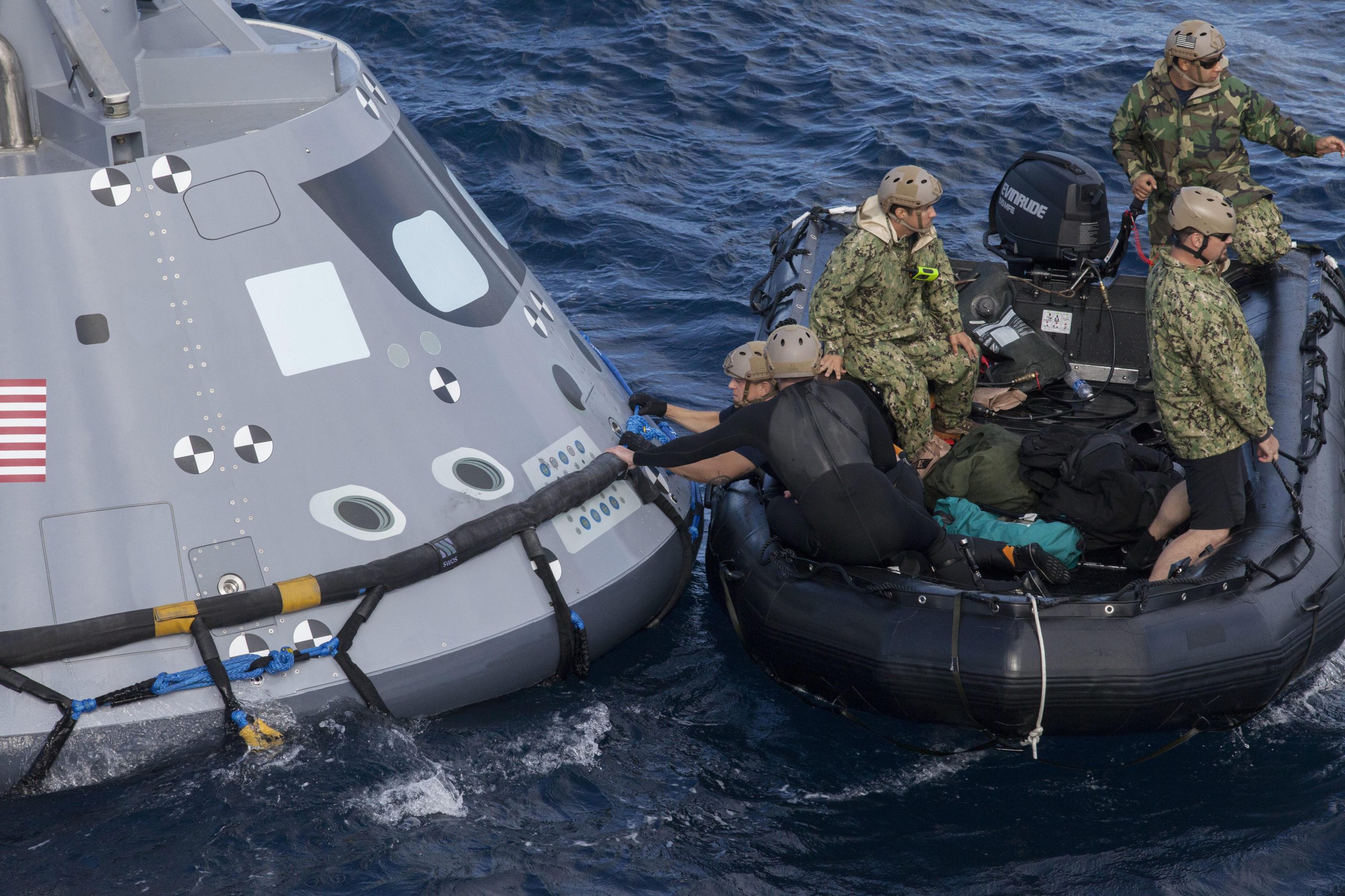Navy divers and other personnel in a Zodiac boat secure a harness around a test version of the Orion crew module during Underway Recovery Test 5 in the Pacific Ocean off the coast of California, Oct. 28, 2016. Members of the New York Air National Guard's 106th Rescue Wing will participate in a mission in Hawaii designed to test space capsule recovery techniques and equipment, although they will not work with a capsule simulator like this one. Orion is the exploration spacecraft designed to carry astronauts to destinations not yet explored by humans. NASA photo. -
