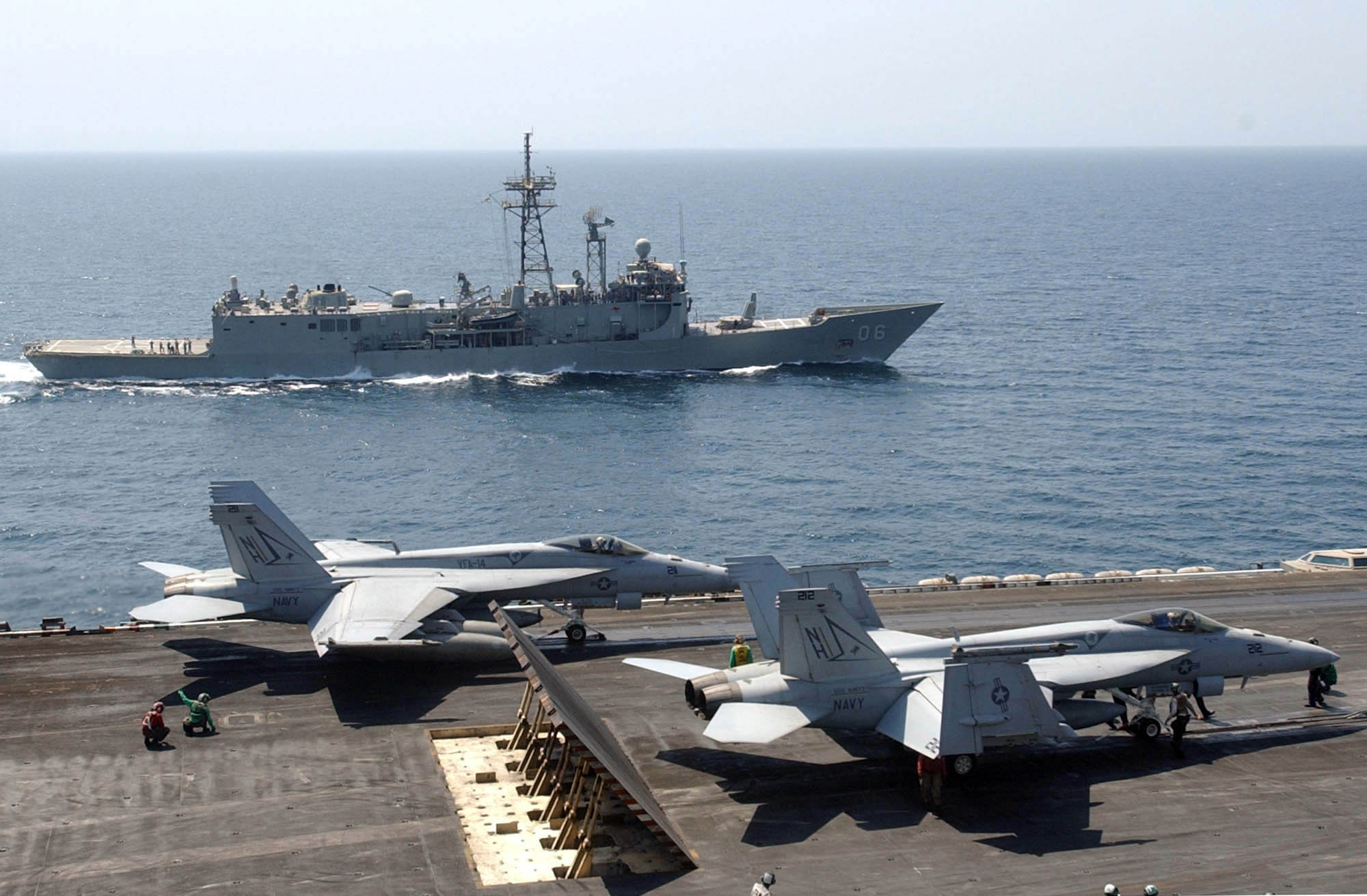 Two F/A-18E Super Hornets, assigned to the "Tophatters" of Strike Fighter Squadron Fourteen (VFA-14), prepare for launch aboard the nuclear-powered aircraft carrier USS Nimitz (CVN 68) as the Royal Australian Navy frigate HMAS Newcastle (FFG 06) cruises alongside. U.S. Navy photo by Photographer's Mate Airman Gretchen Marie Cloonan. -