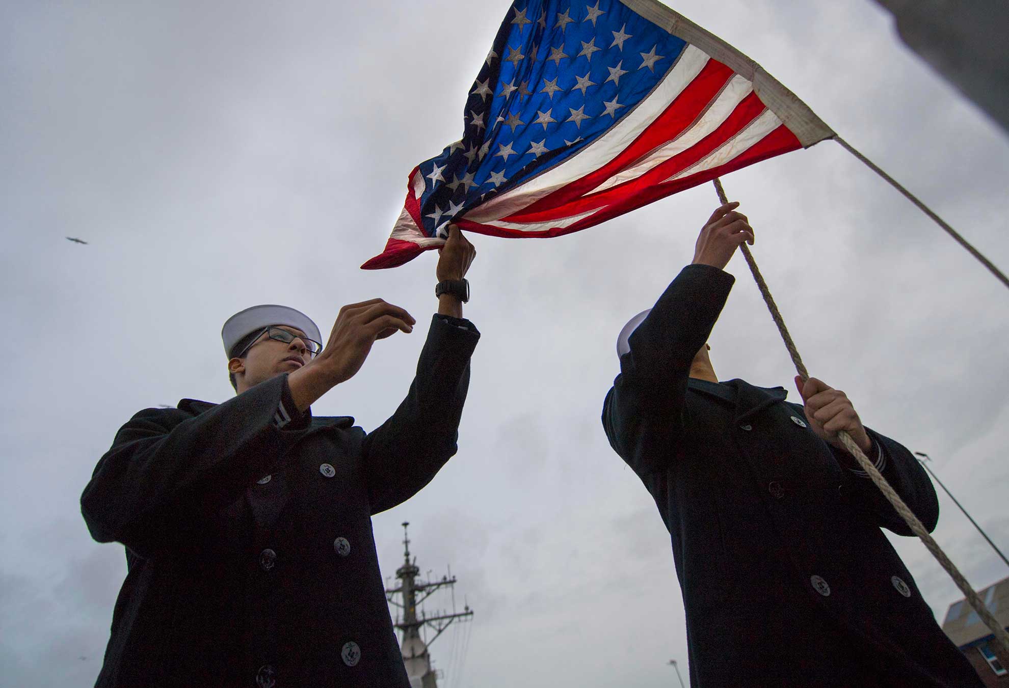 Plymouth, England (Feb. 9, 2019) Seaman Marc Fabien, left, and Fire Controlman 3rd Class Ryan Deguzan hoist the American flag during morning colors aboard the Arleigh Burke-class guided-missile destroyer USS Porter (DDG 78) in Plymouth, England, Feb. 9, 2019. Porter, forward-deployed to Rota, Spain, is on its sixth patrol in the U.S. 6th Fleet area of operations in support of U.S national security interests in Europe and Africa -- U.S. Navy photo by MCS2 James R. Turner. -