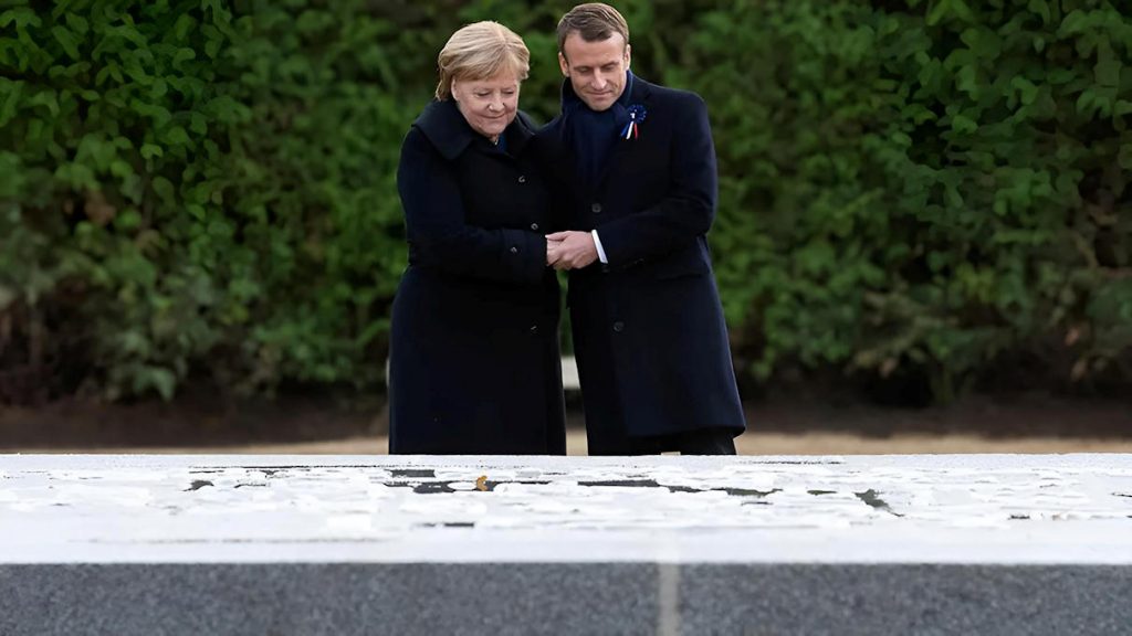 Angela Merkel et Emmanuel Macron main dans la main devant la plaque de l'Armistice, Rethondes, 10 novembre 2018 — le même geste que Kohl et Mitterrand à Verdun trente-quatre ans plus tôt, sans y ajouter de scène nouvelle — Photo © Bundesregierung/Bergmann