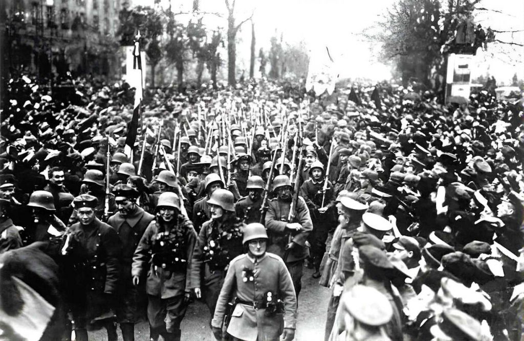 - Berlin Retour des troupes Retour des troupes à Berlin, en décembre 1918 : les soldats, fleuris et couronnés de feuillage en signe d'accueil triomphal, défilent sous les acclamations d'une foule immense. C'est ce jour-là qu'Ebert lance aux régiments : « Aucun ennemi ne vous a vaincus » — une phrase de réconfort patriotique qui deviendra, malgré lui, l'un des piliers du mythe du coup de poignard dans le dos — Photo Bundesarchiv/ Wikipedia