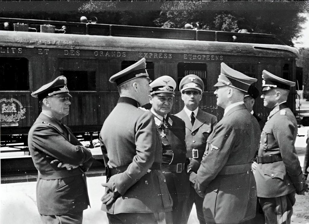 - Bundesarchiv 183 M1112 500 Compiegne Le 21 juin, Ribbentrop, Keitel (de profil), Göring, Hess, Hitler, Raeder (caché par Hitler) et Brauchitsch, devant le wagon de l'Armistice.