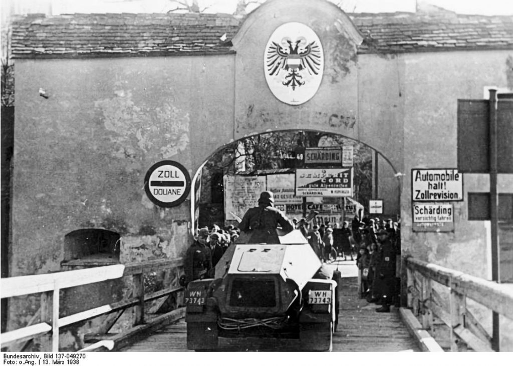 - Bundesarchiv Anschluss Osterreich 1a Un blindé allemand franchit la frontière autrichienne à Schärding, le 13 mars 1938 — jour de la proclamation officielle de l'Anschluss. L'écusson autrichien surplombe encore l'arche, les panneaux de douane sont toujours en place ; dans quelques instants, ils n'auront plus aucun sens. Un an plus tard, à quelques kilomètres de là, ce jour sera immortalisé en pierre à Oberschützen — Photo Bundesarchiv